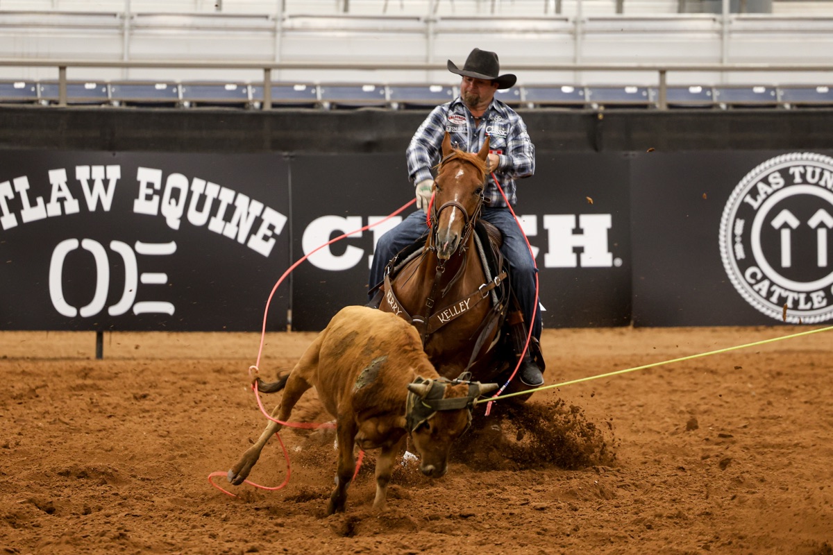 Ryan Motes stopping his rope horse hard in a cloud of dust