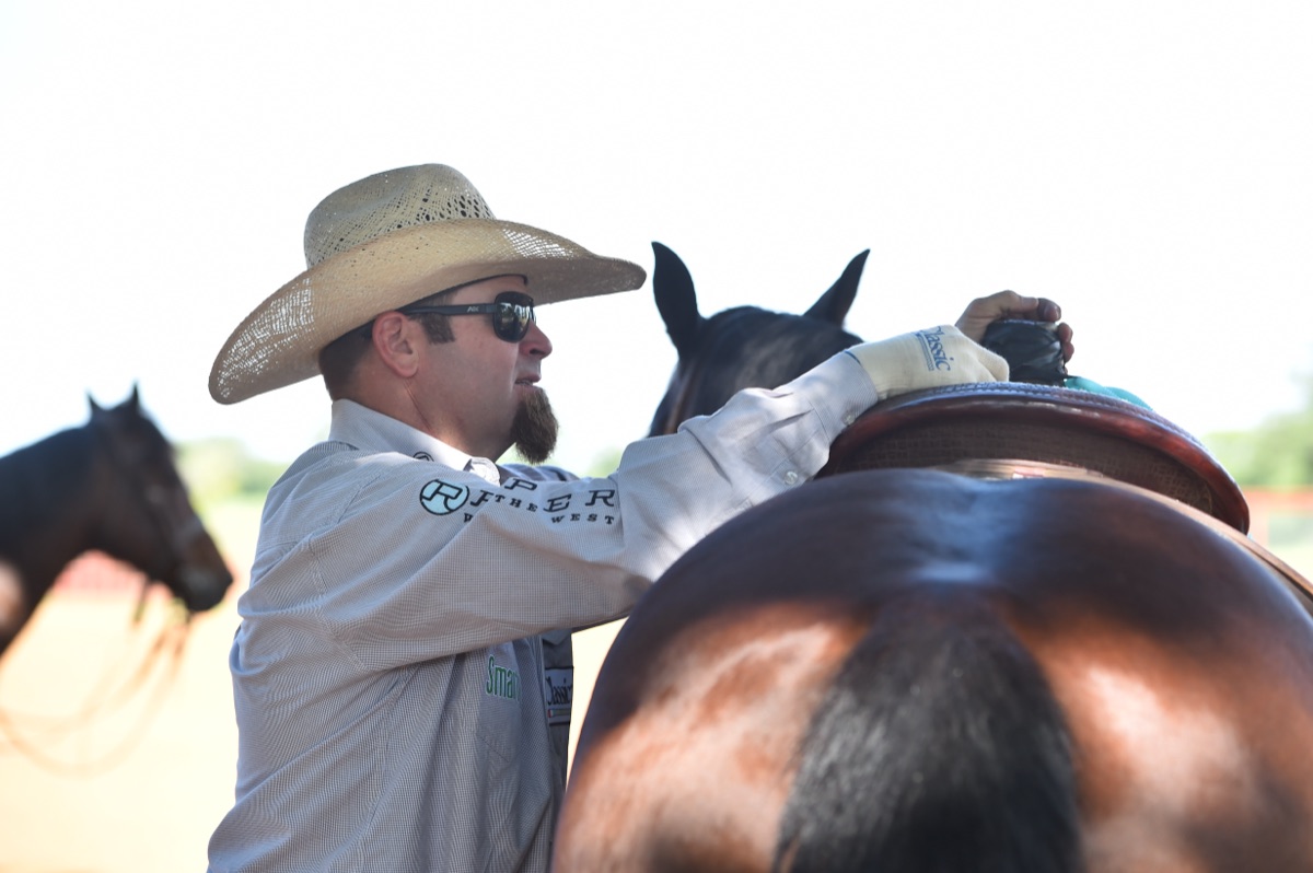 Ryan Motes saddling a horse before a run